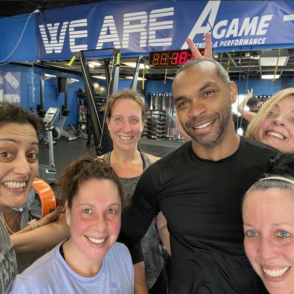 Members and a coach crowding into a happy selfie under the WE ARE A-GAME banner