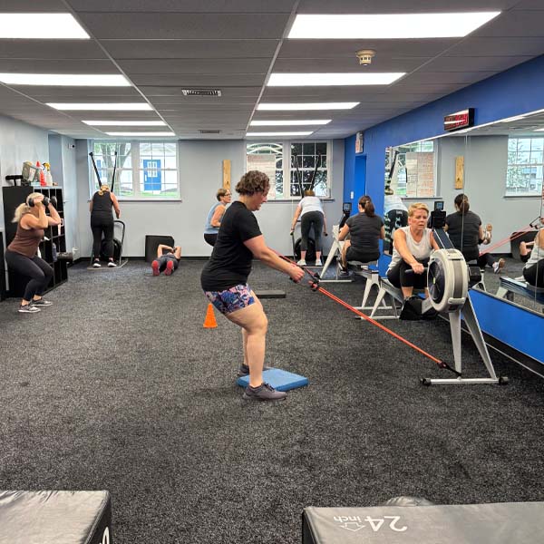 A busy group class mid-workout — rowers, bands and step work