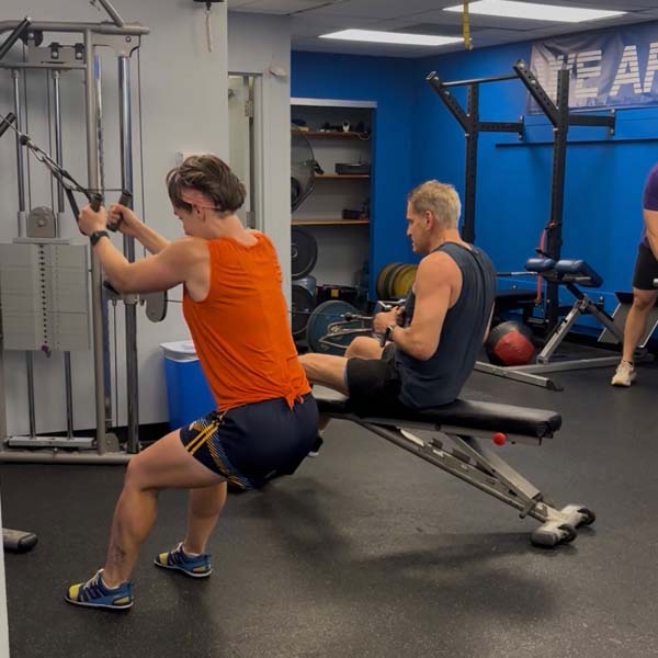 Members training on cable machine and bench in the blue A-Game studio